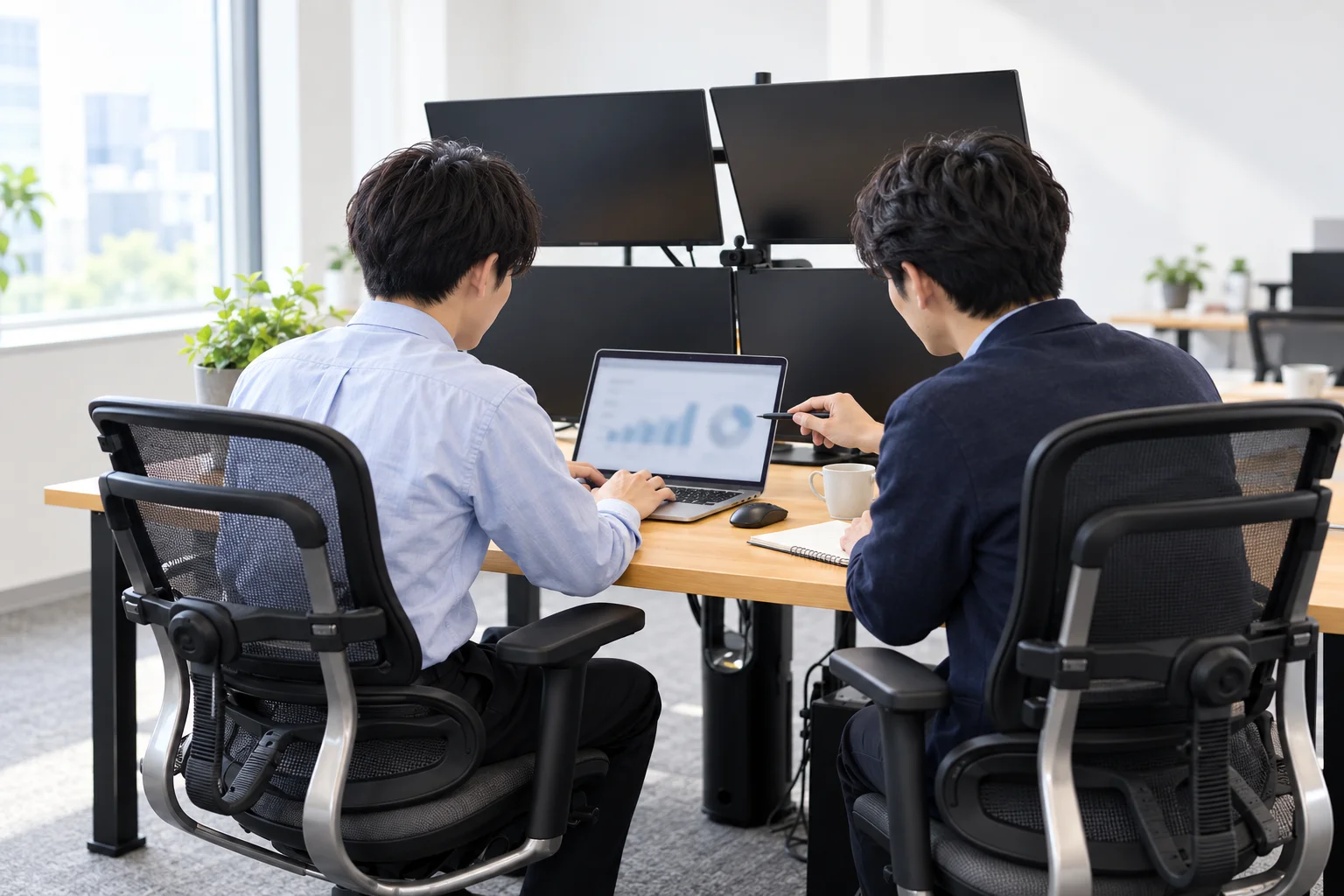 先輩が隣に座り、画面を指しながら教えている